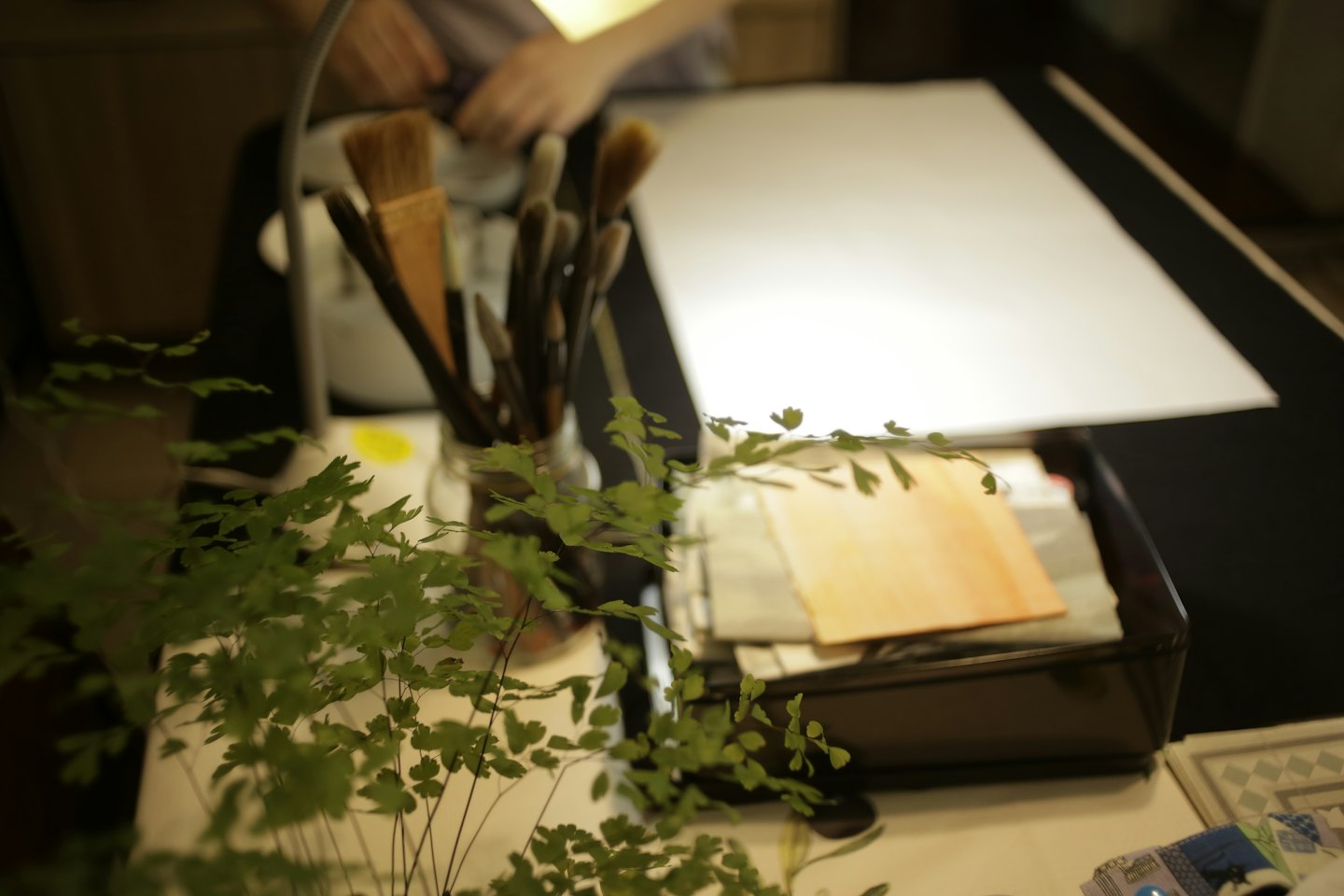 Artist workspace with paintbrushes in a jar and watercolor swatches.