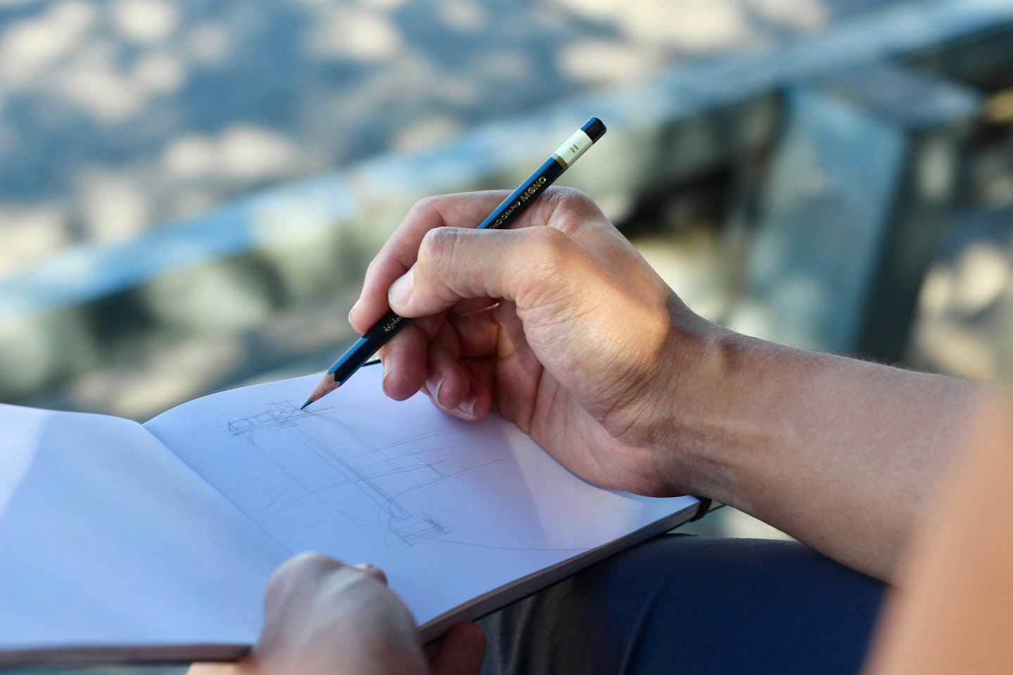 Hands sketching architectural lines in a notebook.